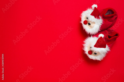 New year, Christmas slippers in form of santa claus with white soft fur on red background with place for text. Funny, cozy, fluffy children shoes. Warm and original gift for the winter holidays