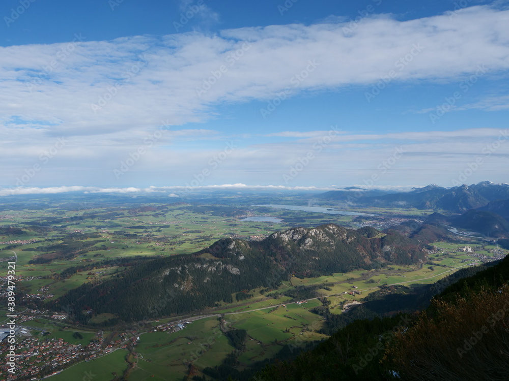 Panoramablick über das Voralpenland bei Füssen im Allgäu in Bayern mit der Burgruine Falkenstein, dem Hopfensee, dem Forggensee und ganz klein in der Ferne Schloss Neuschwanstein