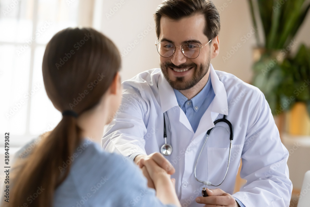 Nice to meet you. Pleasant smiling male doctor meeting young woman patient at clinic, attentive caring physician in charge greeting female client of hospital with handshaking making good impression Nice to meet you. Pleasant smiling male doctor meeting young woman patient at clinic, attentive caring physician in charge greeting female client of hospital with handshaking making good impression