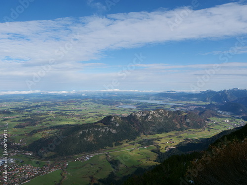 Panoramablick über das Voralpenland bei Füssen im Allgäu in Bayern mit der Burgruine Falkenstein, dem Hopfensee, dem Forggensee und ganz klein in der Ferne Schloss Neuschwanstein