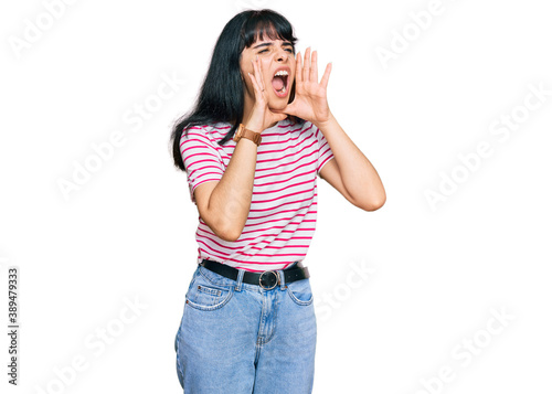 Young hispanic girl wearing casual clothes shouting angry out loud with hands over mouth