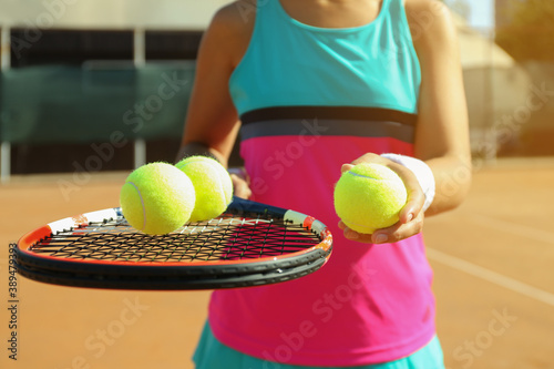 Sportswoman with racket and tennis balls at court, closeup © New Africa