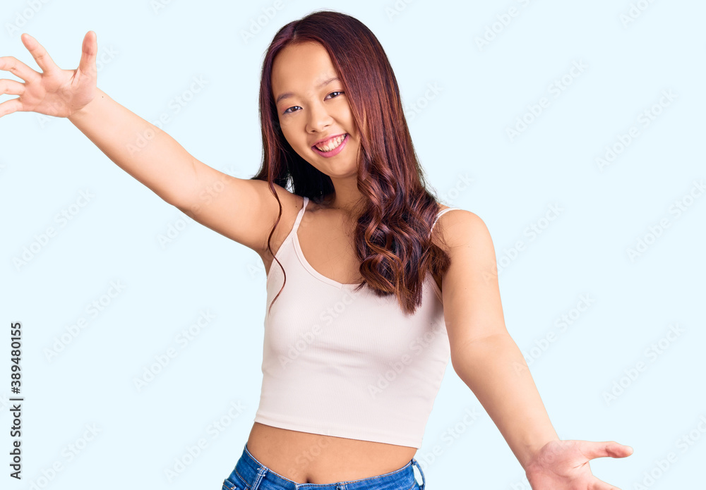 Young beautiful chinese girl wearing casual clothes looking at the camera smiling with open arms for hug. cheerful expression embracing happiness. Young beautiful chinese girl wearing casual clothes looking at the camera smiling with open arms for hug. cheerful expression embracing happiness.