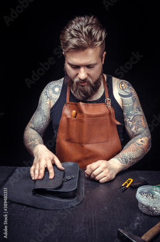 Skinner demostrating leather cutting process in leather shop photo