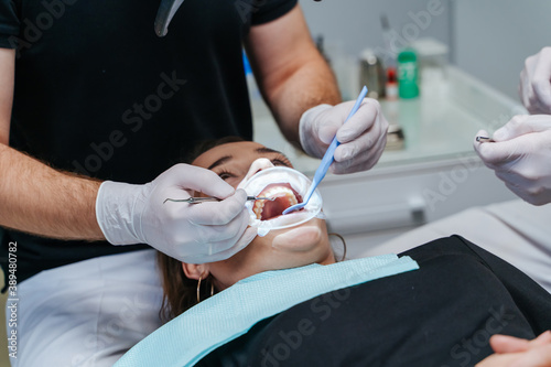 Teeth whitening process. Dentist provides process. Patient in dentist chair. Dental clinic. View from the top. Selective focus.