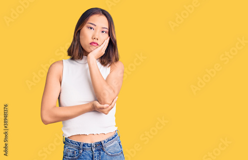 Young beautiful chinese girl wearing casual clothes thinking looking tired and bored with depression problems with crossed arms. © Krakenimages.com