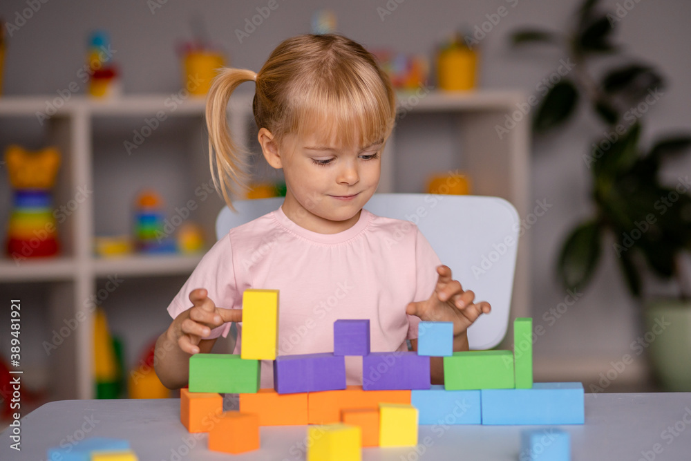 little child girl playing wooden toys at home or kindergarten