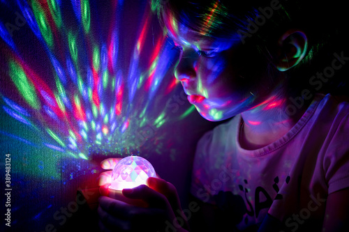Obraz na płótnie Little girl holding a glowing ball with colorful lights in her hands w salonie
