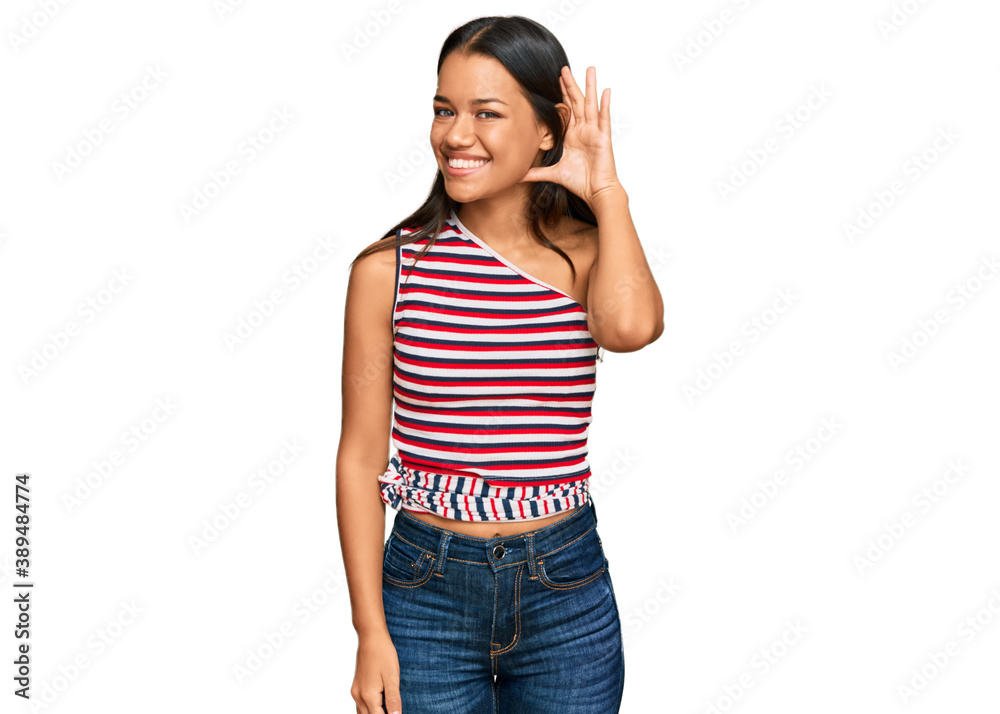 Beautiful hispanic woman wearing casual clothes smiling with hand over ear listening an hearing to rumor or gossip. deafness concept.