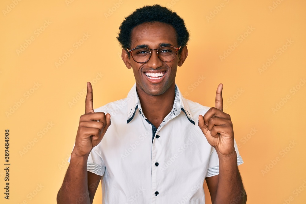 African handsome man pointing up with fingers smiling and laughing hard out loud because funny crazy joke.