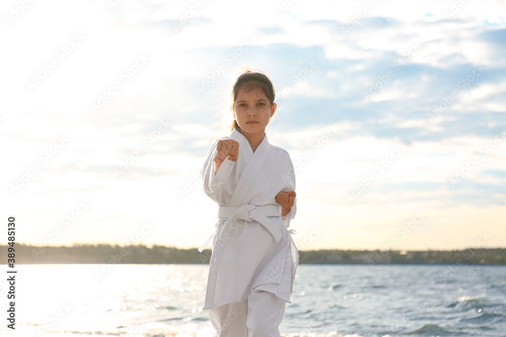 Cute little girl in kimono practicing karate near river Cute little girl in kimono practicing karate near river