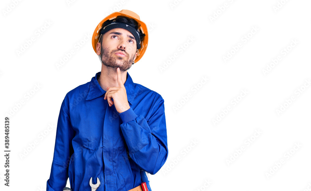 Young hispanic man wearing worker uniform thinking concentrated about doubt with finger on chin and looking up wondering Young hispanic man wearing worker uniform thinking concentrated about doubt with finger on chin and looking up wondering