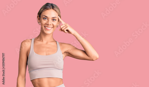 Beautiful caucasian woman wearing sportswear smiling pointing to head with one finger, great idea or thought, good memory