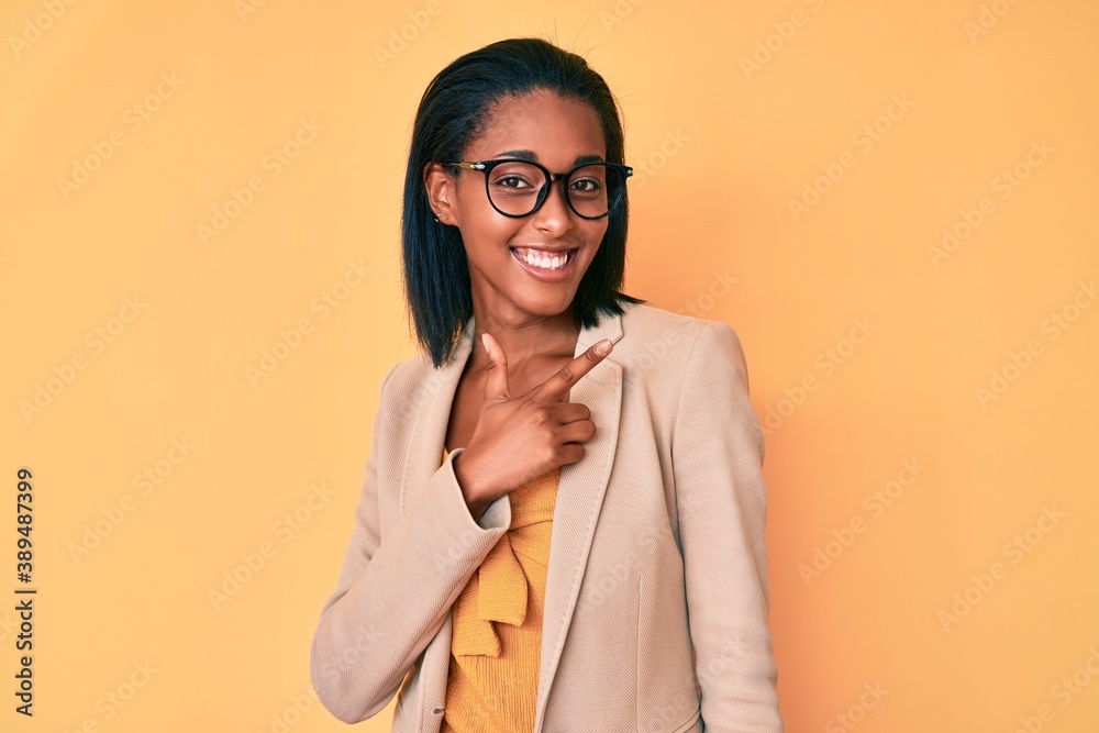 Young african american woman wearing business clothes cheerful with a smile of face pointing with hand and finger up to the side with happy and natural expression on face Young african american woman wearing business clothes cheerful with a smile of face pointing with hand and finger up to the side with happy and natural expression on face