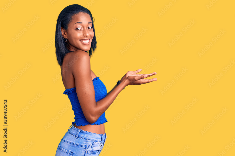 Young african american woman wearing casual summer clothes pointing aside with hands open palms showing copy space, presenting advertisement smiling excited happy Young african american woman wearing casual summer clothes pointing aside with hands open palms showing copy space, presenting advertisement smiling excited happy