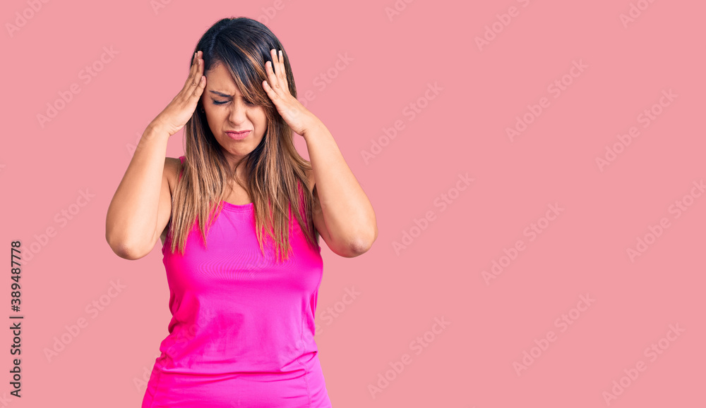 Young beautiful woman wearing sportswear with hand on head for pain in head because stress. suffering migraine. Young beautiful woman wearing sportswear with hand on head for pain in head because stress. suffering migraine.