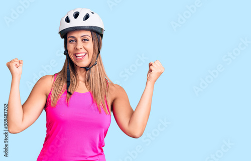 Young beautiful woman wearing bike helmet screaming proud, celebrating victory and success very excited with raised arms