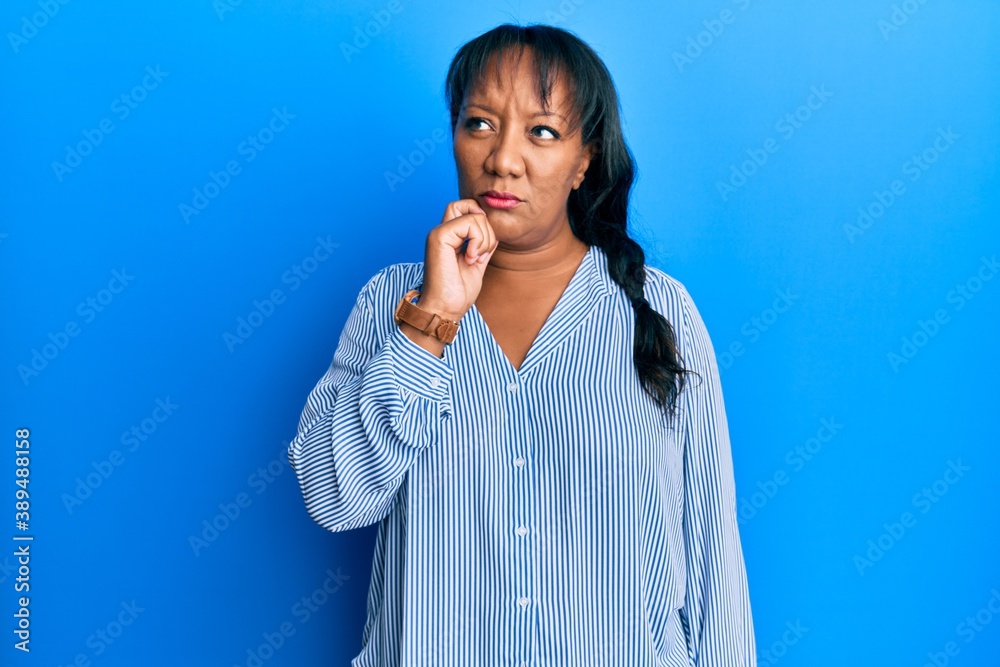 Middle age african american woman wearing casual clothes thinking concentrated about doubt with finger on chin and looking up wondering Middle age african american woman wearing casual clothes thinking concentrated about doubt with finger on chin and looking up wondering