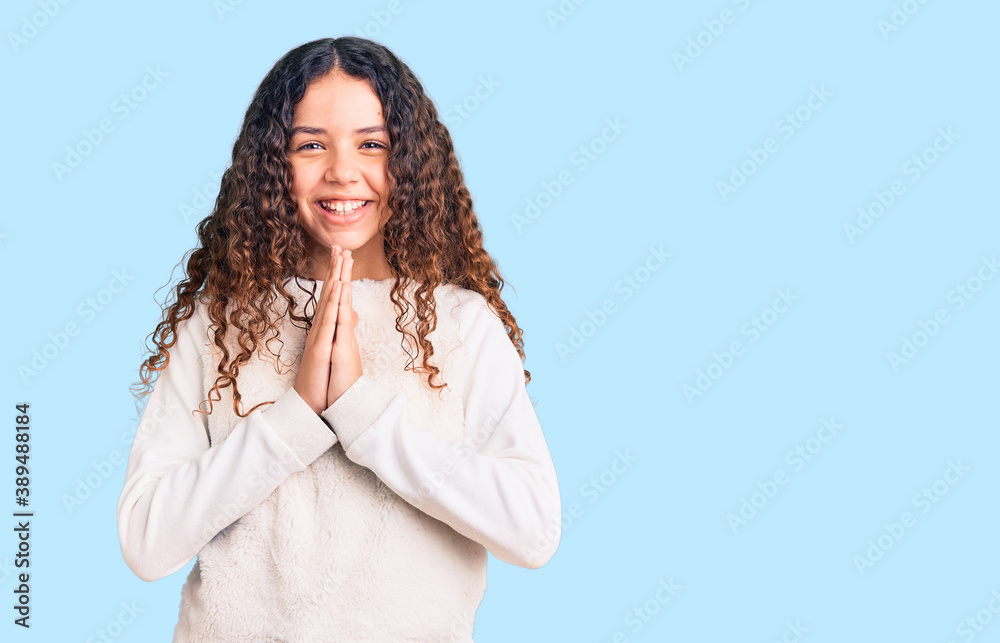 Beautiful kid girl with curly hair wearing casual clothes praying with hands together asking for forgiveness smiling confident. Beautiful kid girl with curly hair wearing casual clothes praying with hands together asking for forgiveness smiling confident.