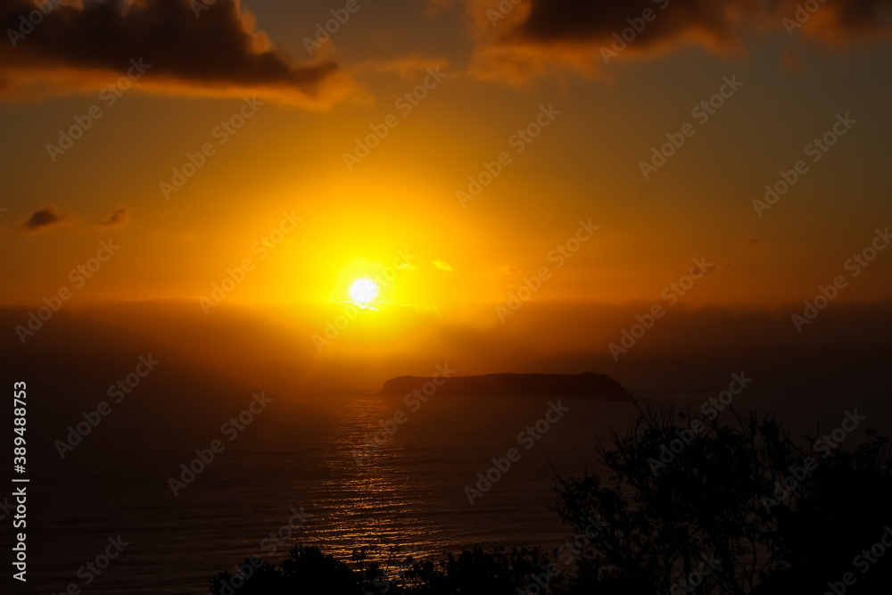 Orange sunrise on the sea behind an island - Mole Beach - Florianópolis, Santa Catarina, Brazil