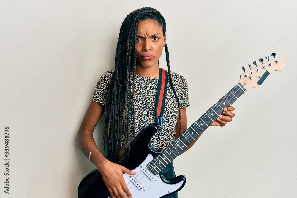 African american woman playing electric guitar skeptic and nervous, frowning upset because of problem. negative person. African american woman playing electric guitar skeptic and nervous, frowning upset because of problem. negative person.
