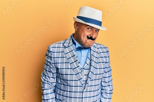 Mature middle east man with mustache wearing vintage and elegant fashion style smiling looking to the side and staring away thinking.