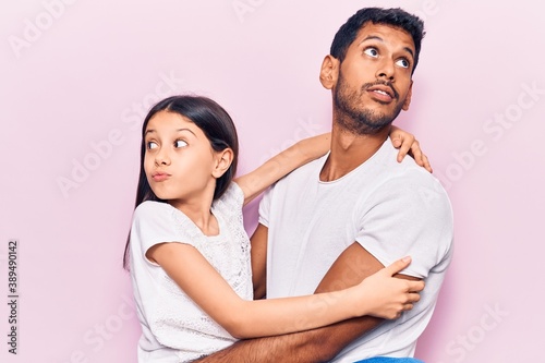 Young father and daughter wearing casual clothes smiling looking to the side and staring away thinking.