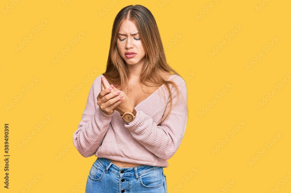 Beautiful blonde woman wearing casual winter pink sweater suffering pain on hands and fingers, arthritis inflammation Beautiful blonde woman wearing casual winter pink sweater suffering pain on hands and fingers, arthritis inflammation