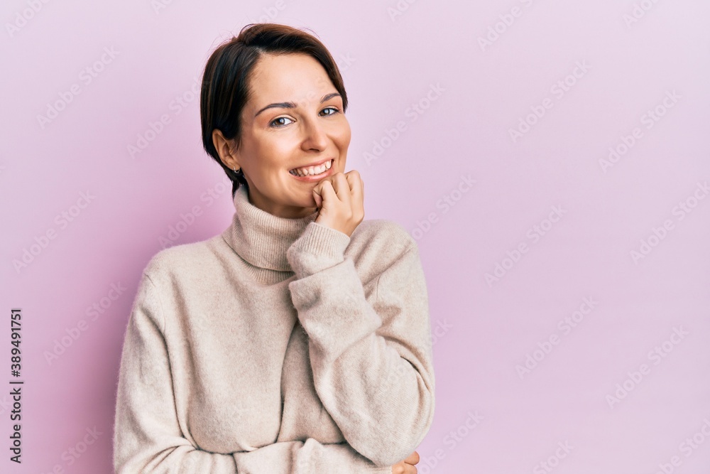 Young brunette woman with short hair wearing casual winter sweater looking confident at the camera with smile with crossed arms and hand raised on chin. thinking positive. Young brunette woman with short hair wearing casual winter sweater looking confident at the camera with smile with crossed arms and hand raised on chin. thinking positive.