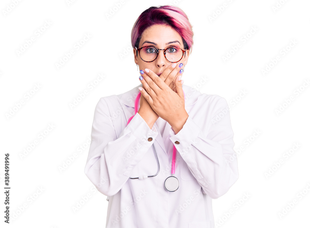 Young beautiful woman with pink hair wearing doctor uniform shocked covering mouth with hands for mistake. secret concept. Young beautiful woman with pink hair wearing doctor uniform shocked covering mouth with hands for mistake. secret concept.