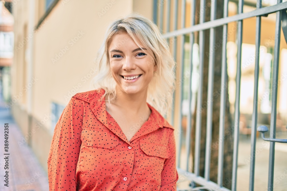 Young blonde woman smiling happy walking at the city.