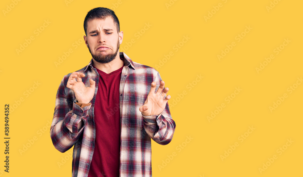 Young handsome man wearing casual shirt disgusted expression, displeased and fearful doing disgust face because aversion reaction. Young handsome man wearing casual shirt disgusted expression, displeased and fearful doing disgust face because aversion reaction.