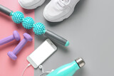 Body roller with shoes, dumbbells, bottle of water and mobile phone on color background