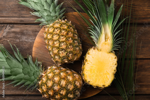 Whole and cut pineapples on wooden table  flat lay