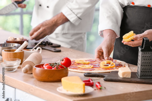 Chefs cooking tasty pizza in kitchen