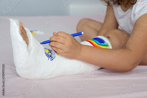 фотографія Teenage girl draws on a leg in a cast
