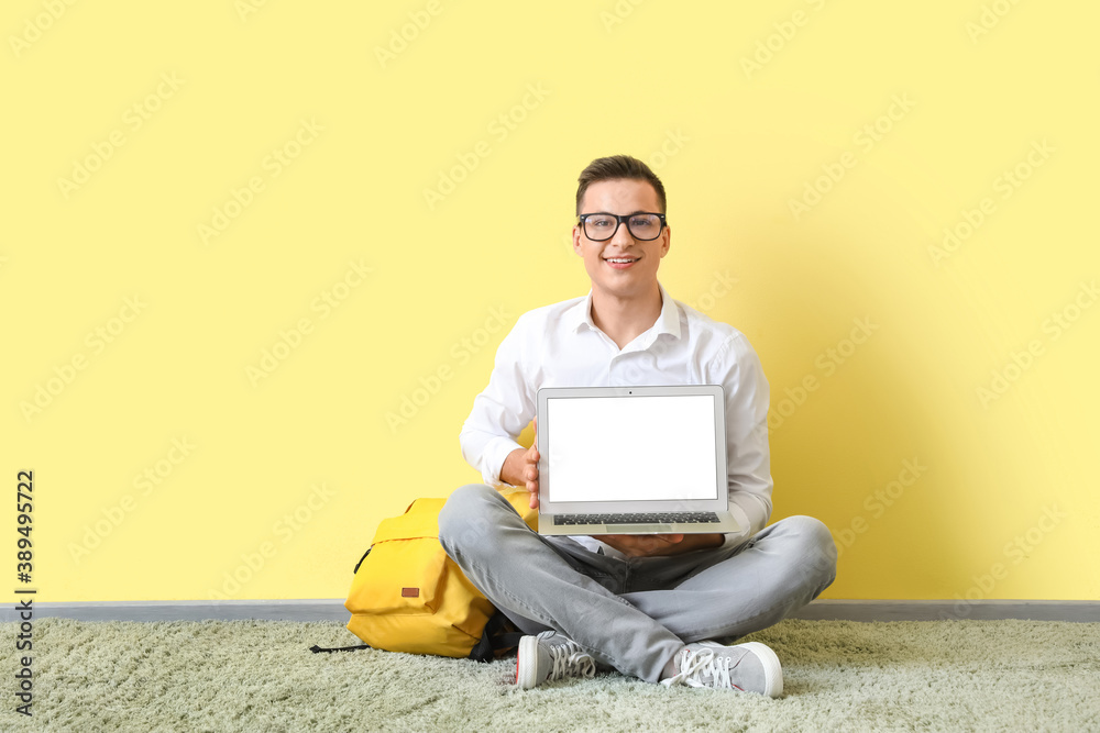 Man with laptop studying online near color wall Man with laptop studying online near color wall