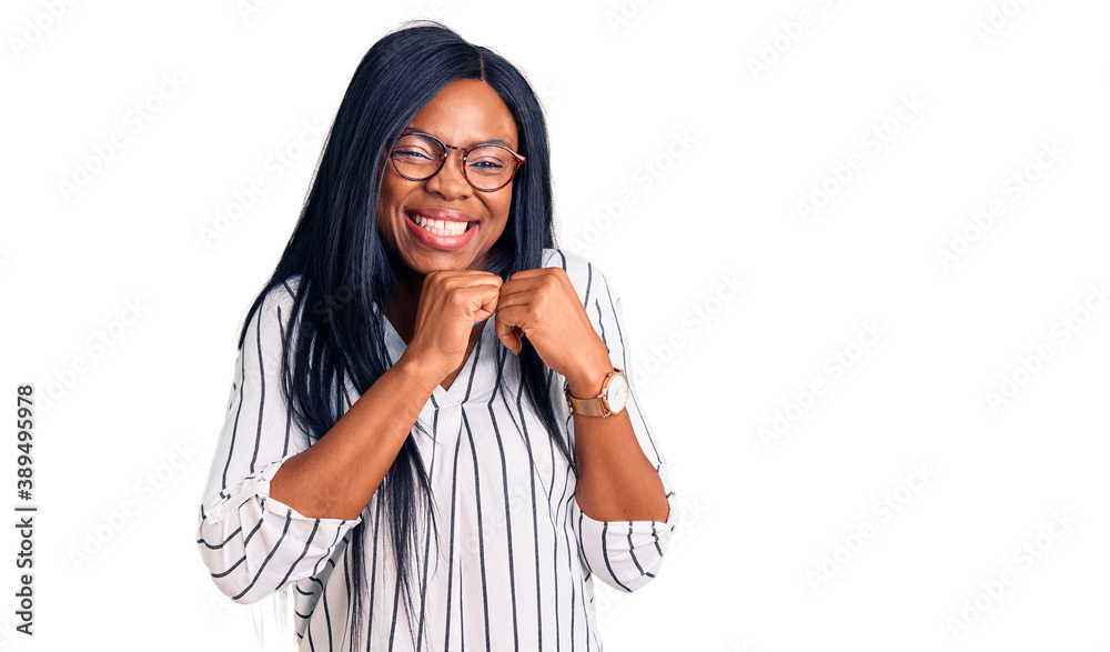 Young african american woman wearing casual clothes and glasses laughing nervous and excited with hands on chin looking to the side Young african american woman wearing casual clothes and glasses laughing nervous and excited with hands on chin looking to the side