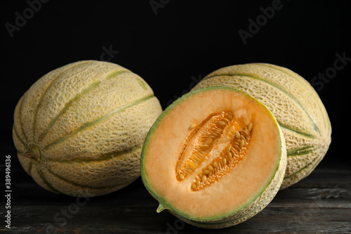 Tasty fresh melons on black wooden table, closeup