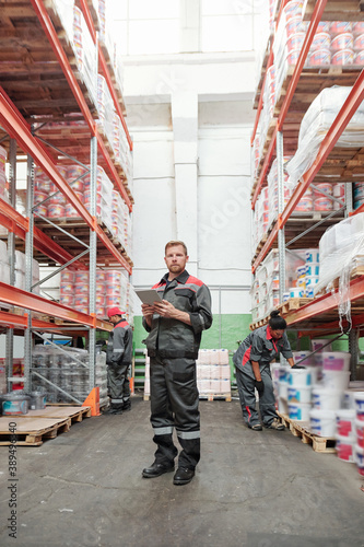 Serious young male manager of warehouse in uniform using digital tablet © pressmaster