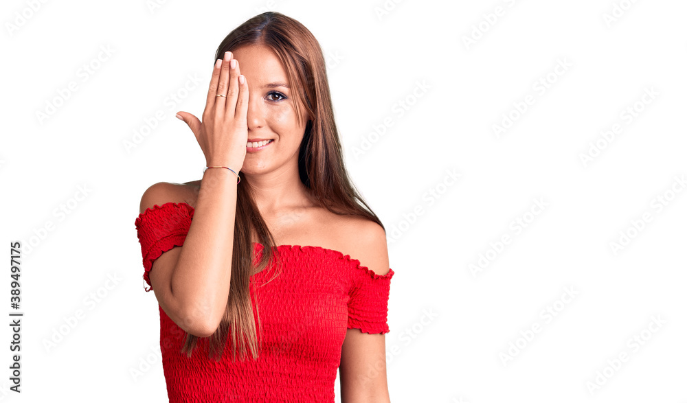 Young beautiful hispanic woman wearing casual clothes covering one eye with hand, confident smile on face and surprise emotion. Young beautiful hispanic woman wearing casual clothes covering one eye with hand, confident smile on face and surprise emotion.