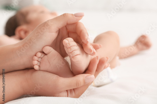 Mother's hands holding tiny legs of her baby, closeup © Pixel-Shot