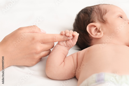 Cute little baby with mother's hand on bed