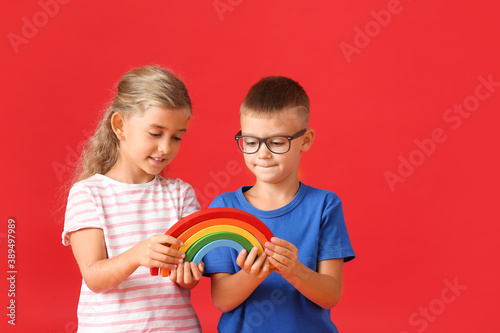 Little children with rainbow on color background