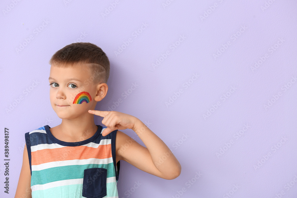Little boy with painted rainbow on his face against color background Little boy with painted rainbow on his face against color background