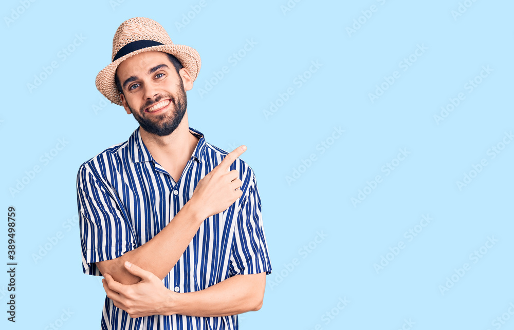 Young handsome man with beard wearing summer hat and striped shirt with a big smile on face, pointing with hand and finger to the side looking at the camera. Young handsome man with beard wearing summer hat and striped shirt with a big smile on face, pointing with hand and finger to the side looking at the camera.