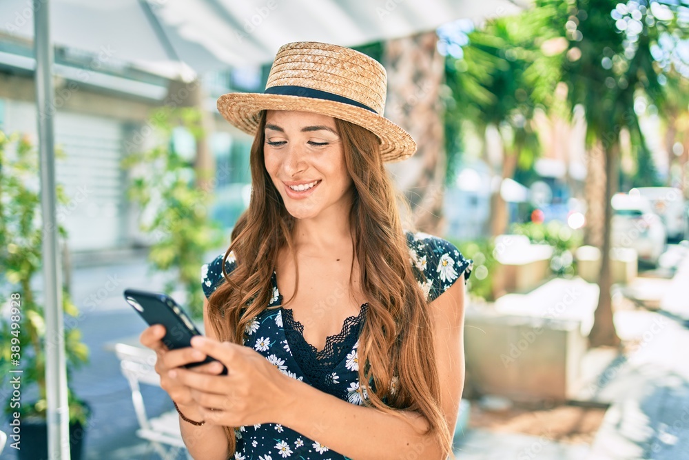 Young hispanic woman on vacation using smartphone at street of city.