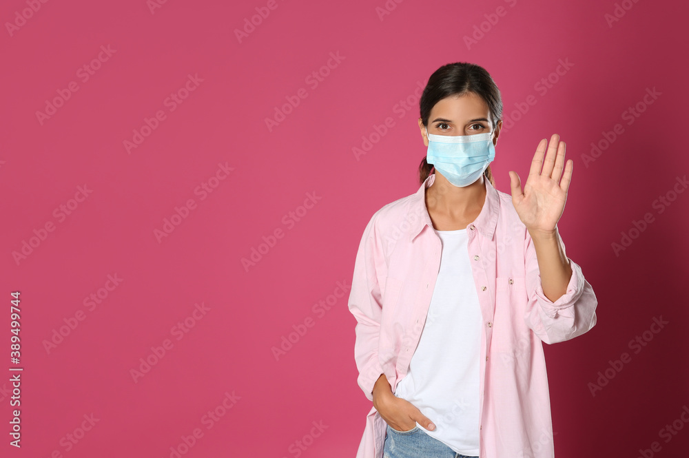 Woman in protective mask showing hello gesture on pink background, space for text. Keeping social distance during coronavirus pandemic Woman in protective mask showing hello gesture on pink background, space for text. Keeping social distance during coronavirus pandemic