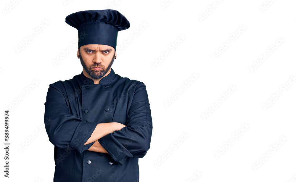 Young hispanic man wearing cooker uniform skeptic and nervous, disapproving expression on face with crossed arms. negative person. Young hispanic man wearing cooker uniform skeptic and nervous, disapproving expression on face with crossed arms. negative person.
