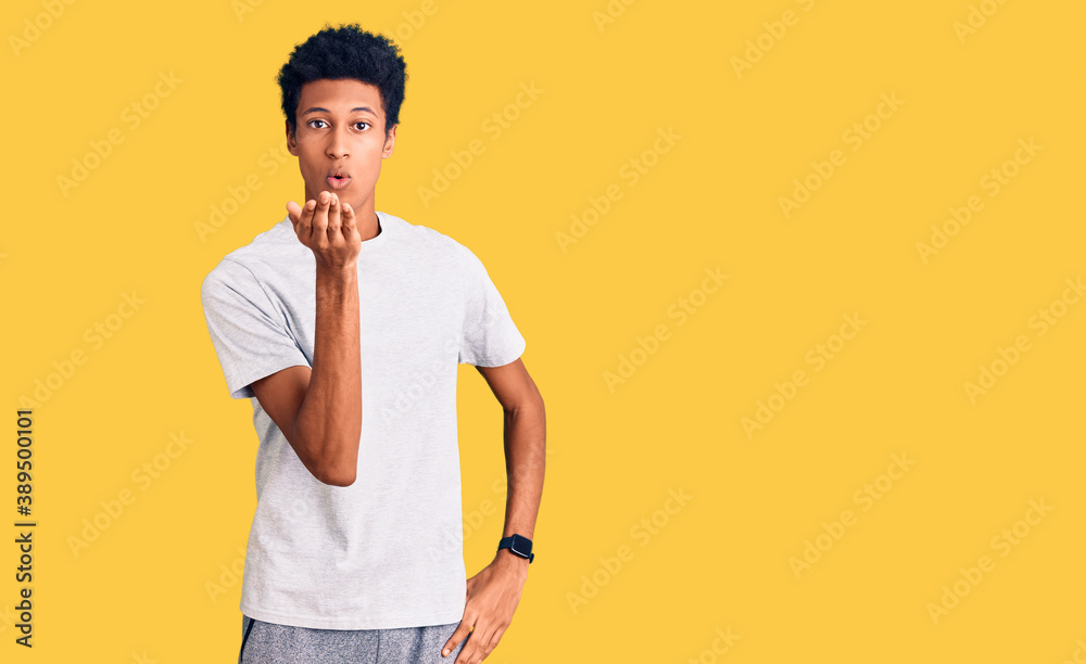 Young african american man wearing casual clothes looking at the camera blowing a kiss with hand on air being lovely and sexy. love expression. Young african american man wearing casual clothes looking at the camera blowing a kiss with hand on air being lovely and sexy. love expression.